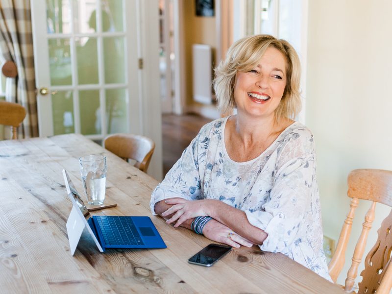 Lynne James laughing at her kitchen table
